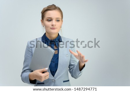 Studio photo a waist-high portrait of a cute young woman girl in a business suit on a white background with a folder in hands. He stands right in front of the camera, explains, with emotion.