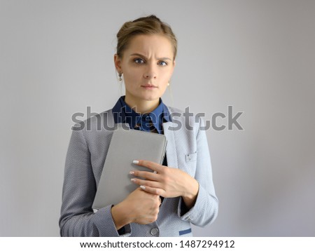 Studio photo a waist-high portrait of a cute young woman girl in a business suit on a white background with a folder in hands. He stands right in front of the camera, explains, with emotion.