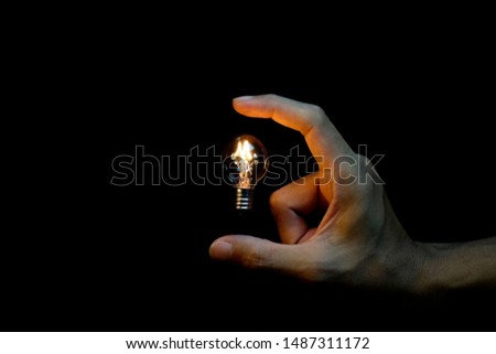        small vintage light bulb in hand and black background,abstract  picture of energy magic concept  and idea thinking                                             