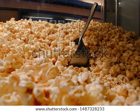 Mountain of Cinema Popcorn in a Popcorn Machine with a shovel / scoop in the Movie Theatre Lobby / Foyer - warm light
