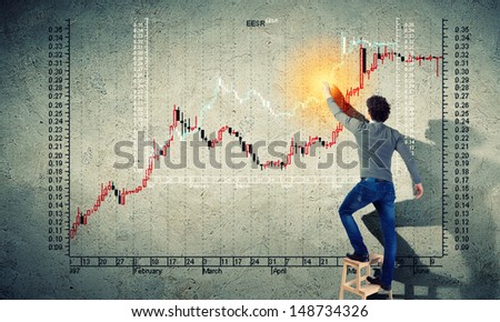 Young man drawing a financial graph on the wall
