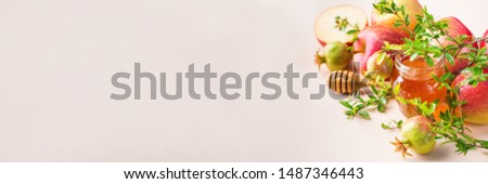 Rosh Hashana, jewish new year holiday concept with traditional symbols, apples, honey, pomegranate on a pastel pink, coral table. Copy space background Royalty-Free Stock Photo #1487346443