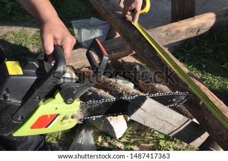 The worker measures the required distance for cutting with a chainsaw.