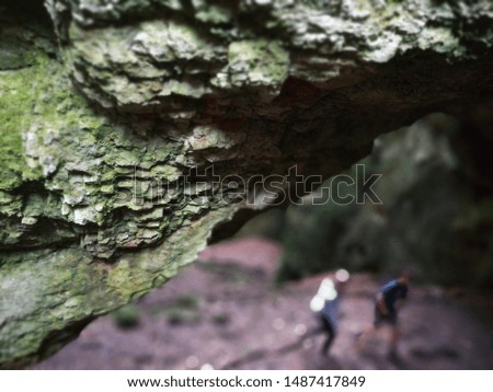 Rock texture with negative, blank space for a poster representing health, hiking, recreation as two people walk in the background out of focus.