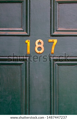 House number 187 on a dark green wooden front door