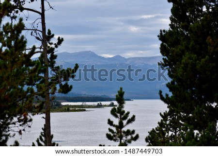 Mountain range over a lake behind pure trees in Montana.