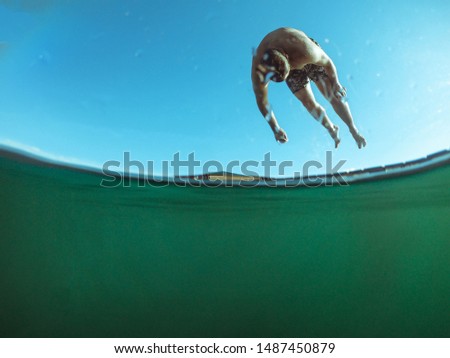 man jumping from wooden pier in lake water summer time