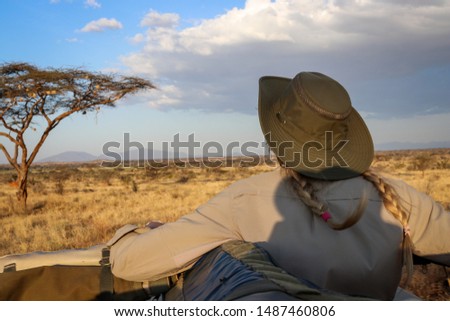 Woman patiently watching outside of a safari car.  Maasai Mara, Kenya 