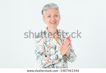 Portrait of a beautiful middle-aged woman. Happy female with gray hair in a jacket looks at the camera standing on a light background.