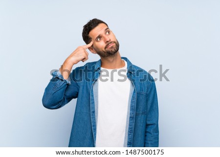 Handsome man over isolated blue background making the gesture of madness putting finger on the head