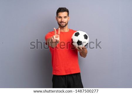 Handsome young football player man over isolated white wall smiling and showing victory sign