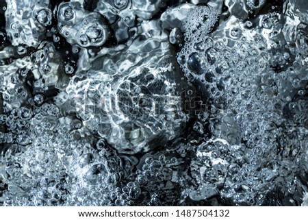 cold clear water flow over stones of the riverbed full frame image