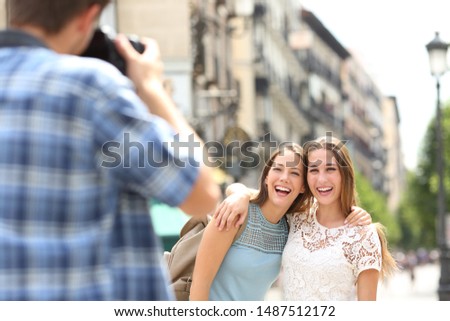 Three happy tourists taking photos with a dslr during vacation travel in a city street