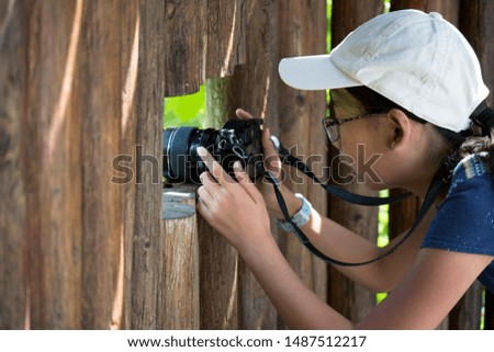 Young little photographer with a digital camera taking photo outdoors