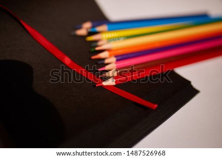 Many colored pencils on a black notebook.
