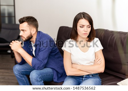 Sad frustrated young couple being in quarrel sitting on sofa in living room and thinking about their problems Royalty-Free Stock Photo #1487536562