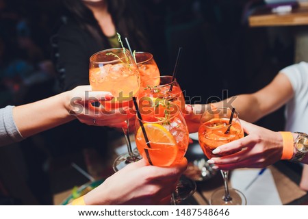 women raising a glasses of aperol spritz at the dinner table. Royalty-Free Stock Photo #1487548646