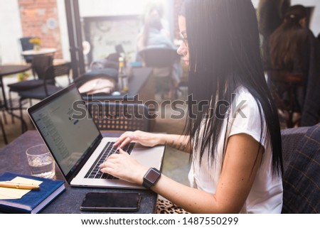 Female skilled copywriter connected to wifi via laptop computer during remote job, sitting in coffee shop outdoors.Hipster girl fashion blogger typing article on notebook gadget, resting in restaurant