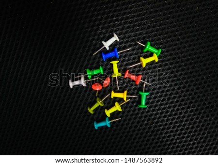 Multicolored pointed pins in black background.