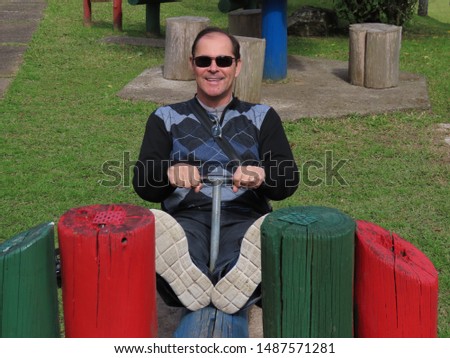 handsome man in his 50s doing poses in a beautiful park with lots of nature