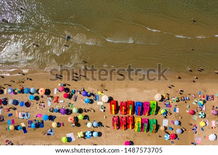 Top view of the beach and water catamarans. People relax on the beach and hide from the sun under sun umbrellas