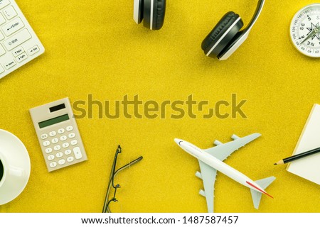Headphone with calculator ,white alarm clock,compass,airplane model and coffee cup on gold glitter texture sparkling shiny paper background.
