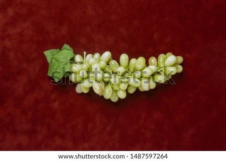 Top view of green grapes over red velvet texture in still life style