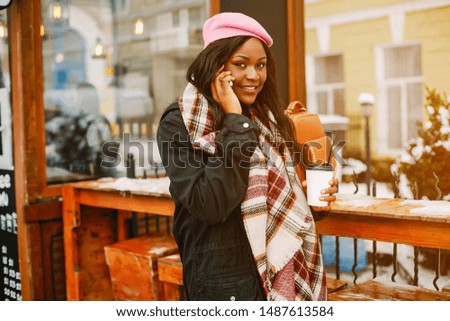 Cute black woman have fun in a city. Beautiful black girl in a pink beret. Stylish lady drinking a coffee. Famale use the phone