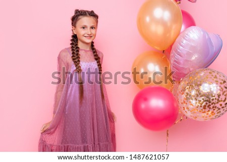 Big surprise, Happy and beautiful teen girl holding a bunch of colorful balloons and looking at camera with smile on pink background