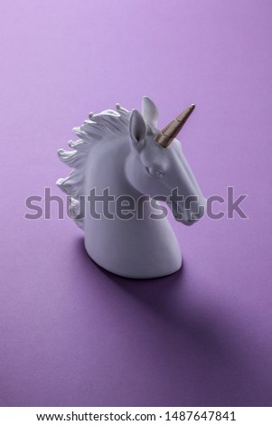 White and gold unicorn head sculpture isolated on purple background