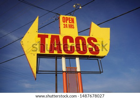 Aged and worn tacos open 24 hours sign                            
