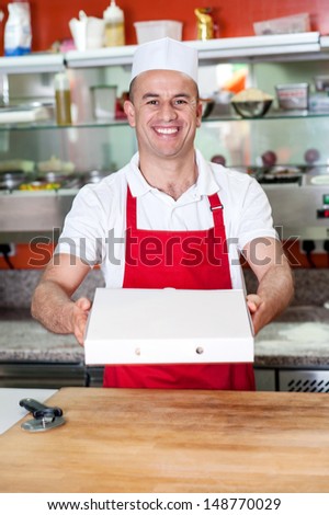 Young male chef handing over pizza