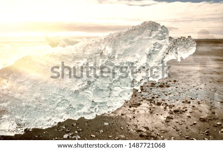 Jokulsarlon Diamond Beach with photographer moving close to iceberg on a sunny day, Iceland. Long exposure view..