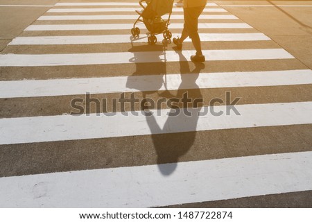 Man as a father and baby in stroller using Zebra crossing way with clean concrete road. Sunset light and shadow on traffic sign area and textured on cement ground. Background for safety first concept.