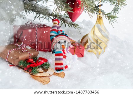 Christmas composition under the Christmas tree - a snowman, boxes with gifts on a sled and other decorations, place for text, copy space