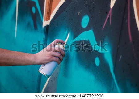 Street artist painting colorful graffiti on generic wall - Modern art concept with urban guy performing and preparing live murales with multi color aerosol spray Royalty-Free Stock Photo #1487792900