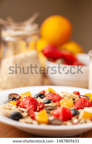 Close-up, Table top image of healthy homemade oats breakfast with strawberry and various fruit toppings in white plate on dining table.