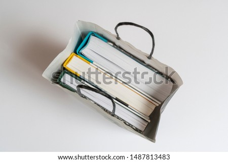 some books inside a white paper bag on the table