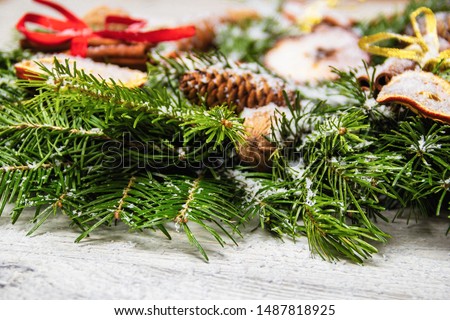 New Year's holiday decorations. Handmade Christmas wreath of fir branches with nuts, cinnamon and dried fruits dusted with artificial snow. 
