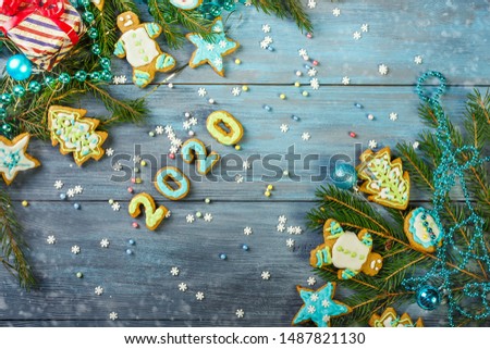 Glazed Christmas gingerbread and Christmas tree branches on a blue wooden background