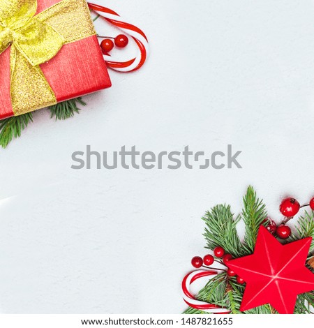 Christmas decor. Red star, gift, green Xmas fir branch, red holly berries and baubles on white stucco plaster texture background. Christmas composition, top view flat lay with copy space