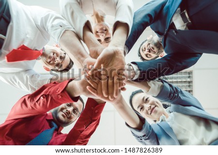 Team of diverse business people stacking their hands together, seen from below Royalty-Free Stock Photo #1487826389