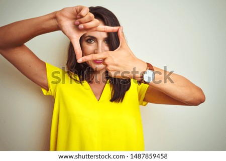 Young beautiful woman wearing yellow t-shirt standing over white isolated background smiling making frame with hands and fingers with happy face. Creativity and photography concept.