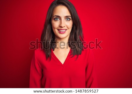 Young beautiful woman wearing shirt standing over red isolated background with a happy and cool smile on face. Lucky person.