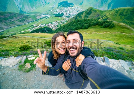 happy tourist backpackers couple taking selfie photo in Stepantsminda also called Kazbegi, Georgia in the Caucasus Mountains