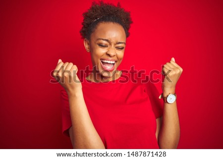 Young beautiful african american woman with afro hair over isolated red background celebrating surprised and amazed for success with arms raised and eyes closed. Winner concept.