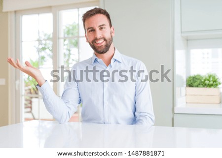 Handsome business man smiling cheerful presenting and pointing with palm of hand looking at the camera.