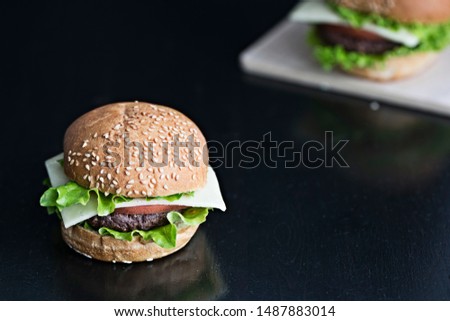 Two burgers on a wooden table, dark background, rustic style