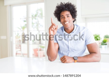 African American business man showing and pointing up with finger number one while smiling confident and happy.