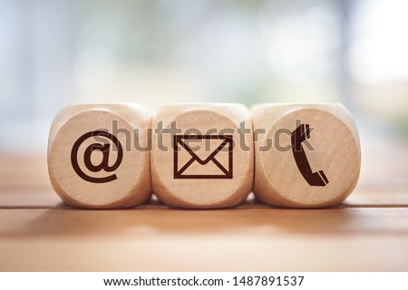 Contact us concept with wood block and symbols at, e-mail address and phone